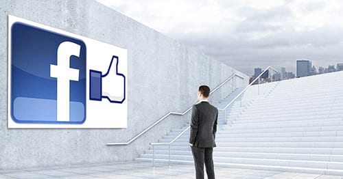 man standing on stairs looking at a facebook logo and like button